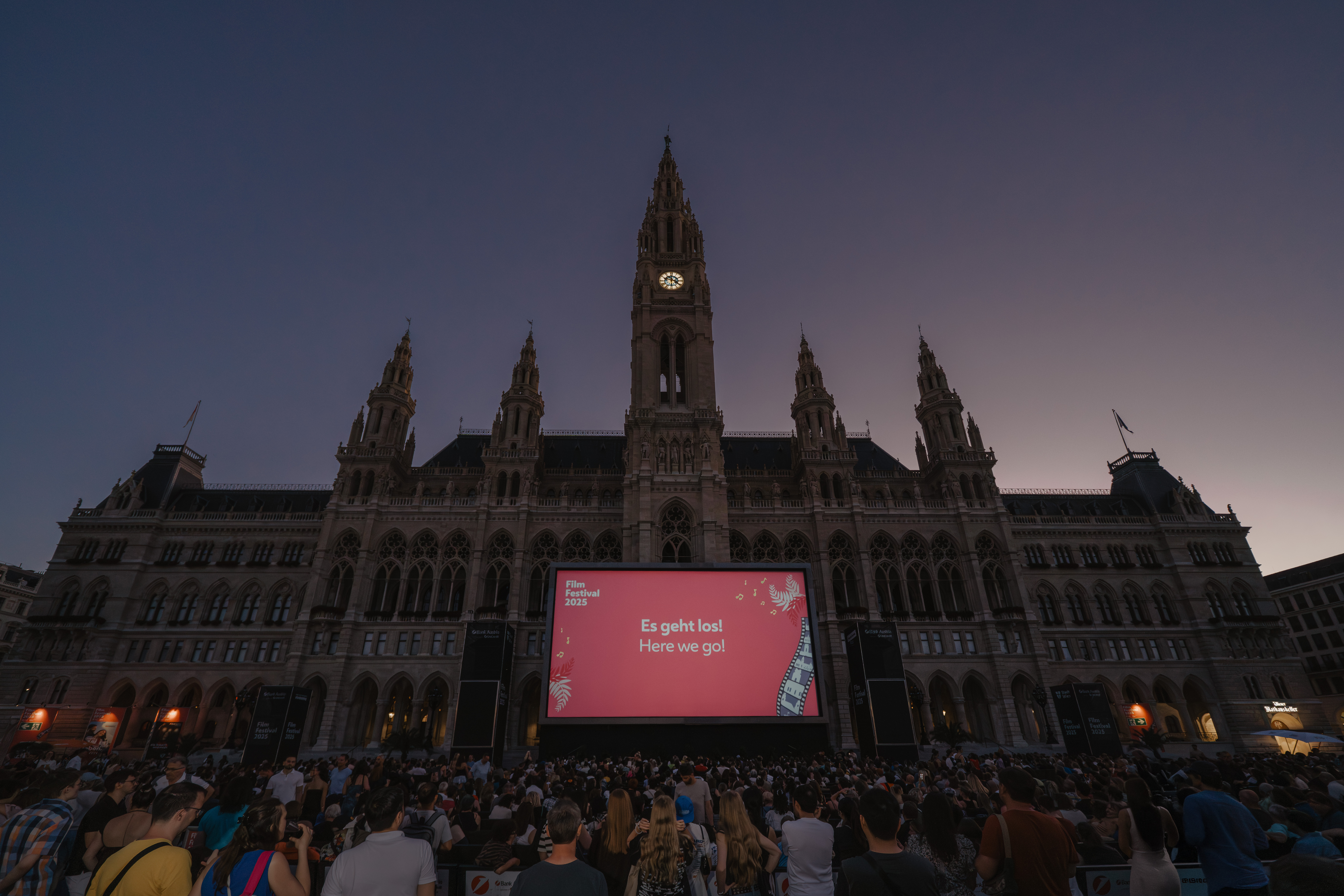 Große Leinwand vor dem Rathaus bei Dämmerung mit Publikum